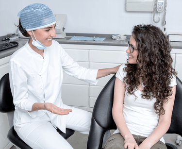 una mujer con camisa blanca y un dentista con bata blanca en una clínica dental