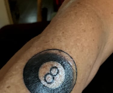 a tattooed arm with a black and white 8-ball tattoo