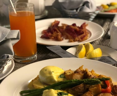Hotel room service breakfast. Orange, bacon,potato, asparagus,lemon on plate.Guest Experience