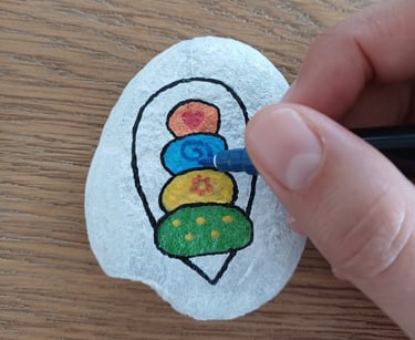 a person's hand holding a pen and drawing on a rock