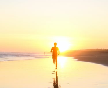 a person walking on a beach at sunset