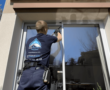 Un employé qui nettoie une baie vitrée