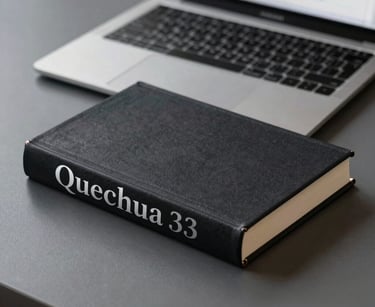 An elegant, minimalist shot of a high-quality hardcover book with 'Quechua' in silver leaf lettering on the spine, resting on a charcoal grey desk. In the background, a modern laptop is open to a translation interface. Sharp focus and prestigious lighting.