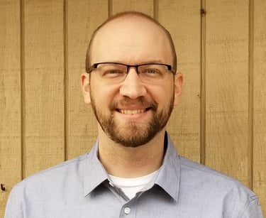 a man with a beard and glasses on a wooden wall