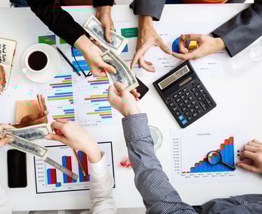 a group of people sitting around a table with money