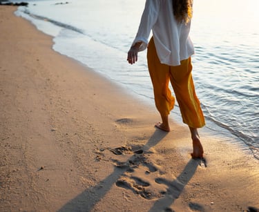 a sugar mommy walking on the beach with her feet in the sand