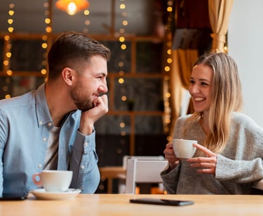 a sugar baby and sugar mommy sitting at a table with a cup of coffee