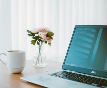 Workspace in the practice of psychotherapist Linda Acikalin with a laptop, coffee cup, and flowers.