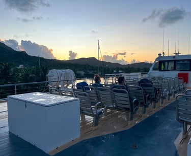 Ferry sailing at sunrise with warm golden light over calm waters in French Polynesia.