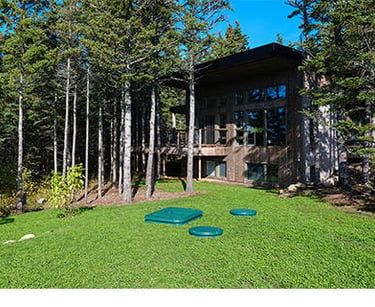 home with dome lids showing of a sanitary sewer aerobic package system with green grass and trees
