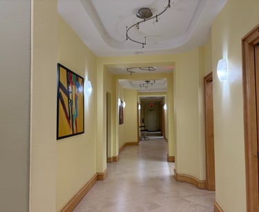A modern yellow office hallway with abstract wall art, tile floors, and contemporary lighting.