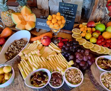 Gourmet charcuterie board with sliced Gruyere and Emmental cheese, fresh grapes, nuts, and tropical fruits.