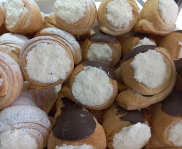 Variedad de conitos dulces de hojaldre rellenos de crema y algunos bañados en chocolate sobre mostra