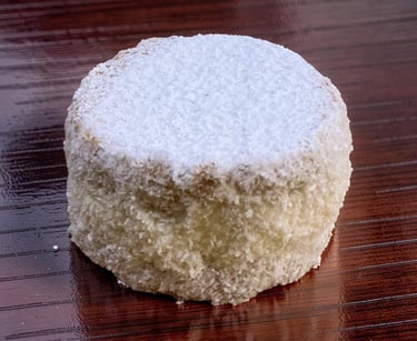 A round shortbread cookie dusted with powdered sugar on a dark wood surface.