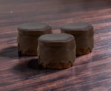 Three chocolate-covered biscuits sitting on a dark wooden table background.