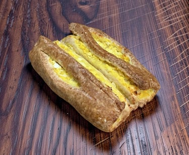Golden brown puff pastry filled with creamy egg salad on a dark wood table.