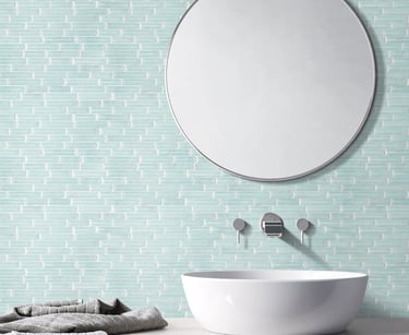 a bathroom sink with a mirror and a towel, green glass mosaic on the background wall