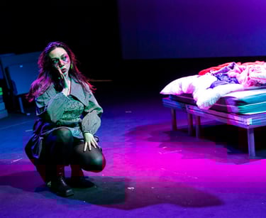 A filipina woman in a structured grey jacket crouched on a purple stage