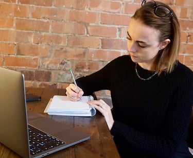 Coach Moll sat in front of laptop writing in her notebook