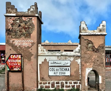 Crumbling buildings at Tizi n'Tichka with sign reading 'Col du Tichka Alt 2260m'