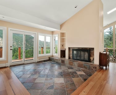a living room with a fireplace and a fireplace with wood and stone flooring - Montana