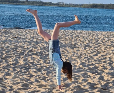 a happy person doing a handstand on a Sunshine Coast beach