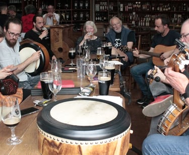 Musicians playing traditional Irish music instruments including banjo, guitar, and bodhrán in a pub.