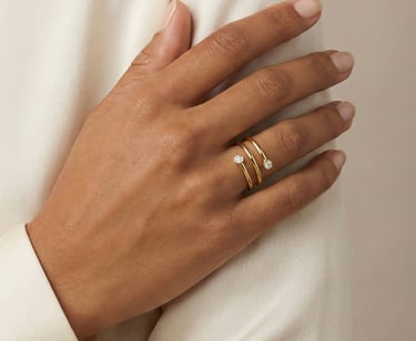 Una persona que lleva en el dedo un anillo envolvente de oro de 14 quilates con dos diamantes redond