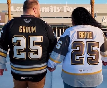 a man and woman holding hands and wearing matching hockey jerseys