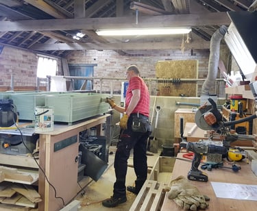 a man in a workshop painting a garden planter