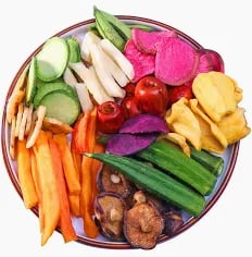 A colorful variety of crispy dried vegetable chips on a plate, featuring okra, sweet potato, and beet.