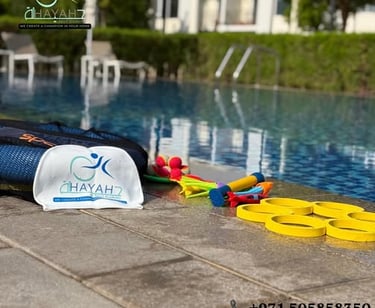 Swimming gear including a branded swim cap and colorful training toys by a luxury outdoor pool.