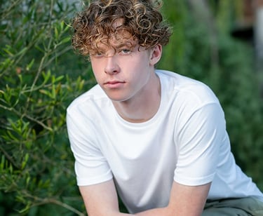 a young man sitting on a bench in a park