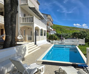 The photo depicts the house and yard with the pool as seen from the western sunny terrace.