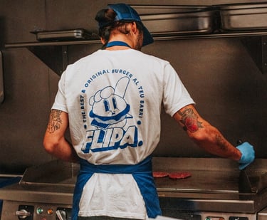 Cocinero de Flipa cocinando carne en la plancha con camiseta oficial de la marca