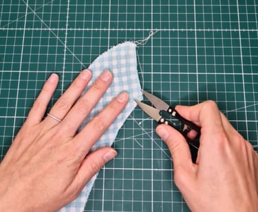 a person cuts a loose thread from a piece of fabric with thread cutters