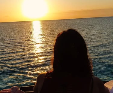 Silhouettes of tourists enjoying the serene Zanzibar sunset on a traditional dhow cruise.