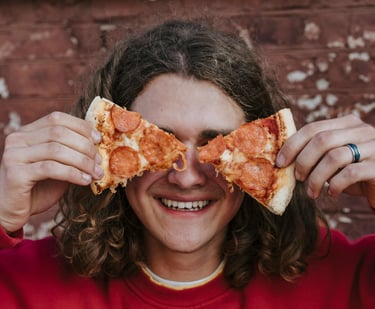 Un adolescent avec des parts de pizza devant ses yeux
