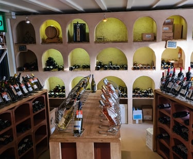 Rustic wine cellar and retail shop featuring arched wall alcoves and racks of red and white wine bottles.