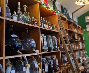 Vintage wine and liquor shop interior with glass carboys, wooden shelves, and tasting dispensers.