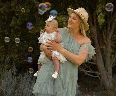 Woman with hat holding her baby playing with bubbles