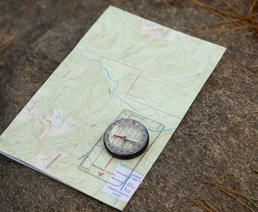 Compass resting on topographic map on forest ground, essential tool for orienteering and survival navigation