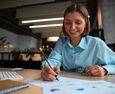 a woman in a blue shirt is smiling and holding a pen