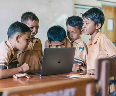 a group of children in school uniforms looking at a laptop