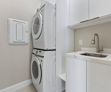 Laundry with stack washer and dryer, sink and lots of storage cabinet