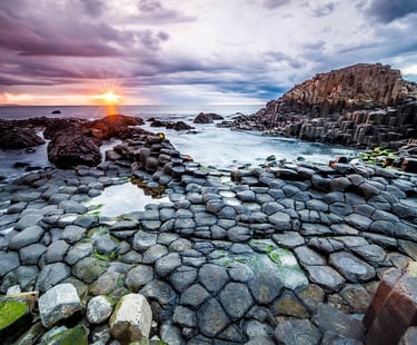 a sunset over a rocky beach with a sunset