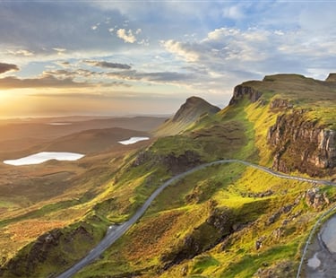a winding road in the mountains with a sunset