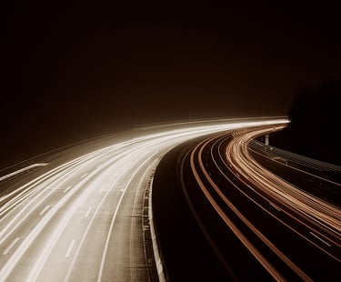 luces de coches en via rápida por una autopista de noche.