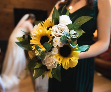 a woman in a green dress holding a bouquet of wedding flowers
