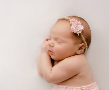 a baby girl sleeping on her side with her hands on her chin